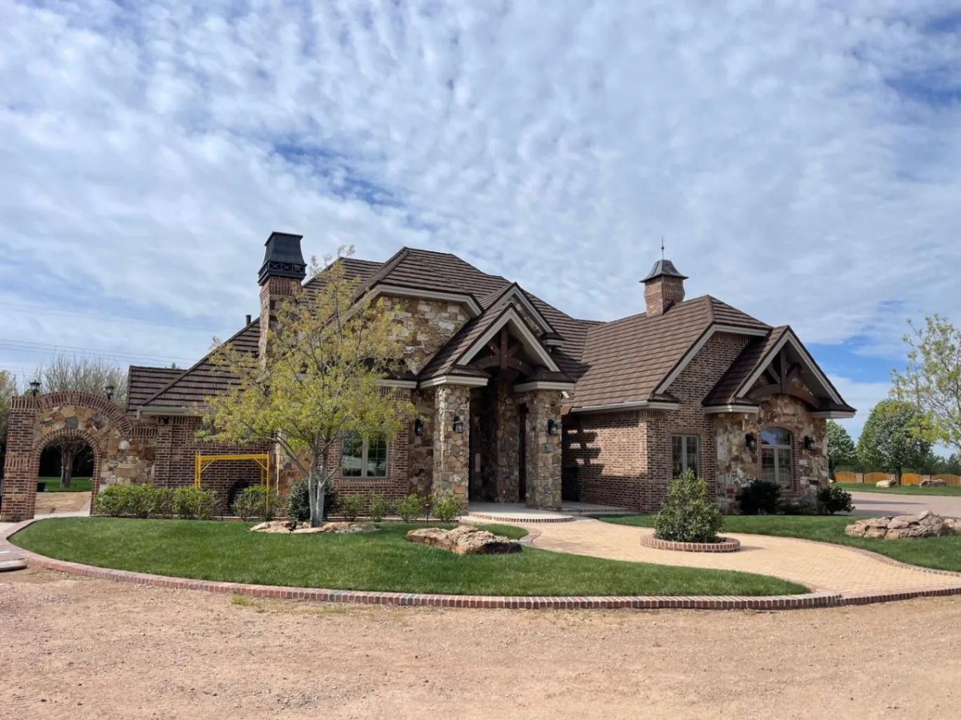 Large brick and stone home with brown tile roof