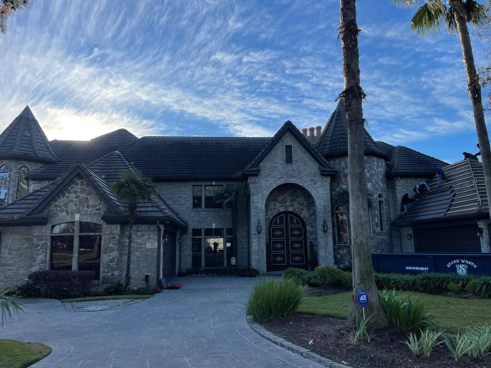 Large custom stone estate with turret towers and dark tile roofing